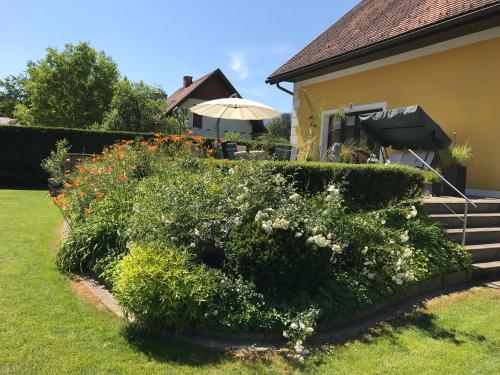 a hedge with flowers in front of a house at Lauras Ferienwohnung - Ihr Wohlfühlort in der Südweststeiermark in Eibiswald
