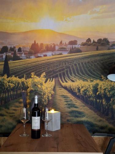 a table with wine glasses and a painting of a vineyard at Lauras Ferienwohnung - Ihr Wohlfühlort in der Südweststeiermark in Eibiswald