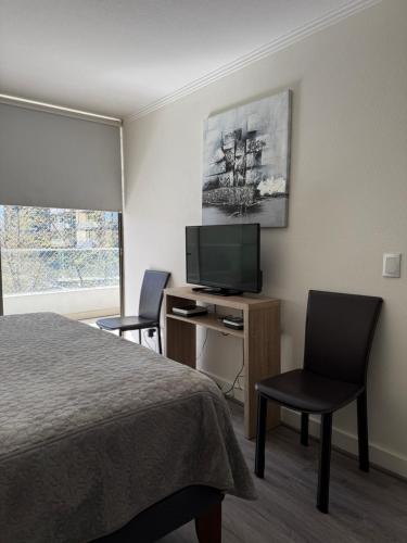 a hotel room with a bed and a desk with a television at Depto a 2 pasos Mall Parque Arauco 301 in El Cerrillo