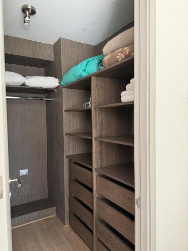 a walk in closet with wooden shelves and pillows at Depto a 2 pasos Mall Parque Arauco 301 in El Cerrillo