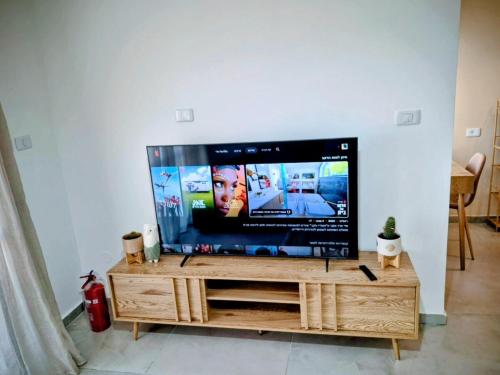a flat screen tv sitting on top of a wooden entertainment center at נחת רוח Nachat Ruach in Mitzpe Ramon