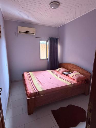 a bedroom with a bed with pink sheets and a window at Appartement de 2chambres in Kofa