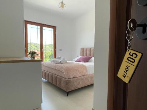a bedroom with a bed and a chair and a window at Bujtina ALDOR in Berat