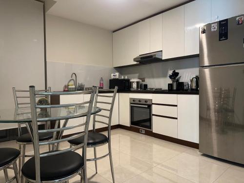 a kitchen with a glass table and a stainless steel refrigerator at Marina Luxe Appartment in Dehiwala