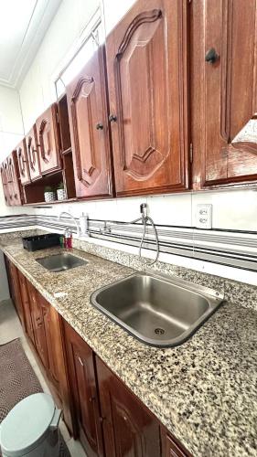 a kitchen counter with a sink and wooden cabinets at Comfortable house in Pedreira in Belém