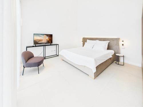 ティミショアラにあるGriselini Boutique ApartHotelのベッドと椅子のある白い寝室