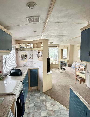a kitchen with blue cabinets and a living room at Herons mead 12 in Addlethorpe