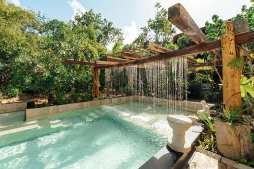an outdoor swimming pool with a wooden pergola at ARKA Tulum in Tulum