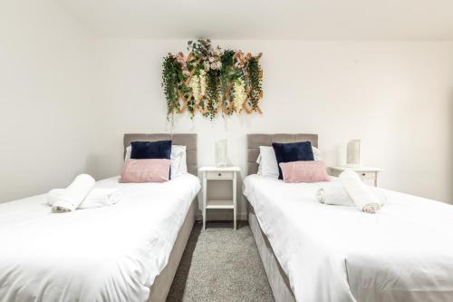 two beds with white sheets and a wreath on the wall at KGV Stays Millbrook Executive Smart Corporate Apartment with Excellent City Links in Southampton