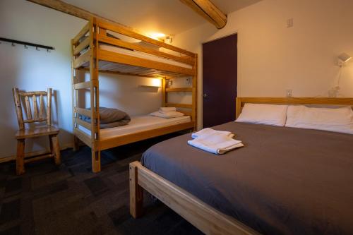 a bedroom with two bunk beds and a chair at HI Nordegg - Hostel in Nordegg