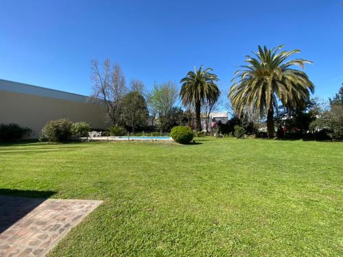 a grassy yard with palm trees and a building at La Quinta de Areco in San Antonio de Areco
