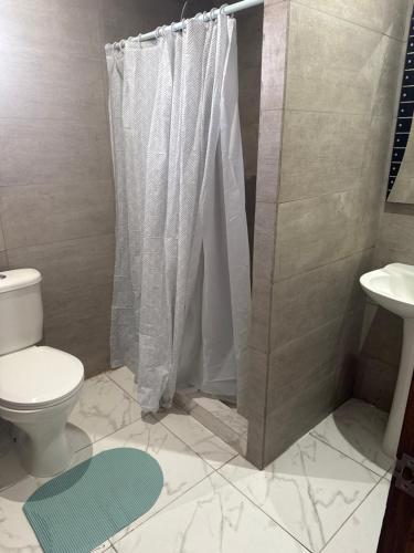 a bathroom with a shower curtain and a toilet at Cabañas Alibe in Los Vilos