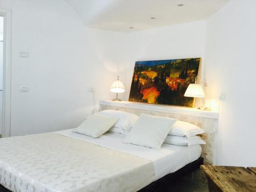 a white bedroom with a white bed with two lamps at Trullidea in Alberobello
