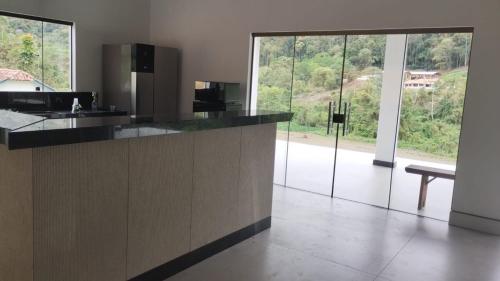 a kitchen with a counter with a bench and windows at Casa Uliana Aracê Pedra Azul in Domingos Martins