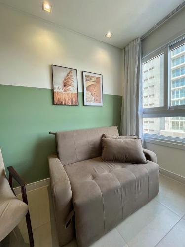 a brown couch in a living room with a window at Apto Home & Club em Capão da Canoa in Capão da Canoa