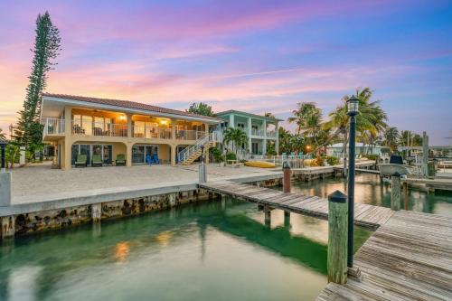 Sunset Harbor Waterfront Villa with Dock Cabana Club في Key Colony Beach: منزل على رصيف بجوار تجمع للمياه