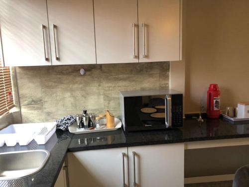 a kitchen counter with a microwave and a sink at Eastern Road Executive Suites in Harare
