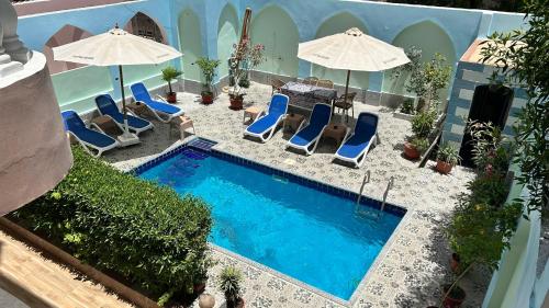 a swimming pool with chairs and umbrellas and a table at Luxor palace Apartments in Luxor