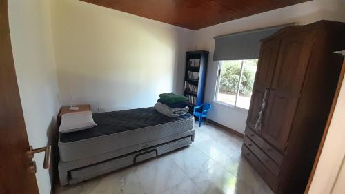 Un dormitorio pequeño con una cama y una ventana. en La casita del bosque, en Valeria del Mar