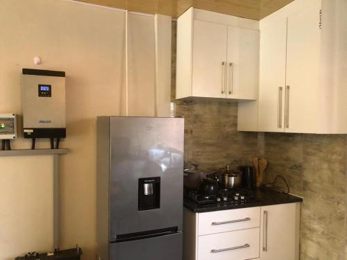 a kitchen with white cabinets and a stainless steel refrigerator at Eastern Road Executive Suites in Harare