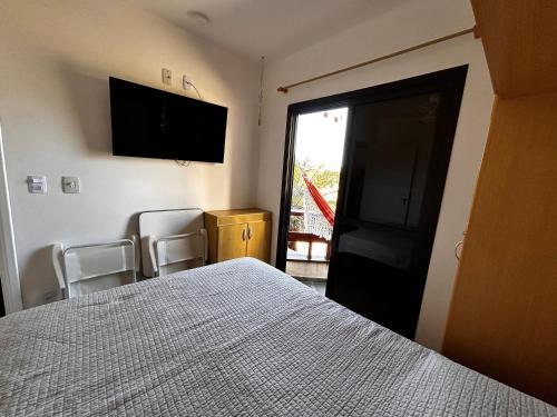 a bedroom with a bed and a flat screen tv at Flat encantador com lazer in Serra Negra