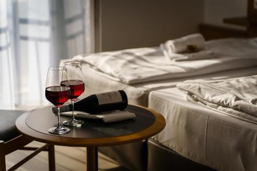 two glasses of wine on a table next to a bed at Hotel Waibstadter Hof in Waibstadt