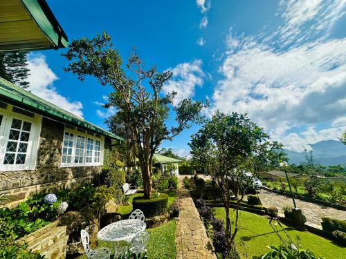 a garden with white chairs and a house at The Bloomsdale Country House in Haputale