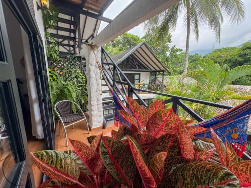 a balcony with a hammock and palm trees at Hostal Antawara Tayrona in El Zaino
