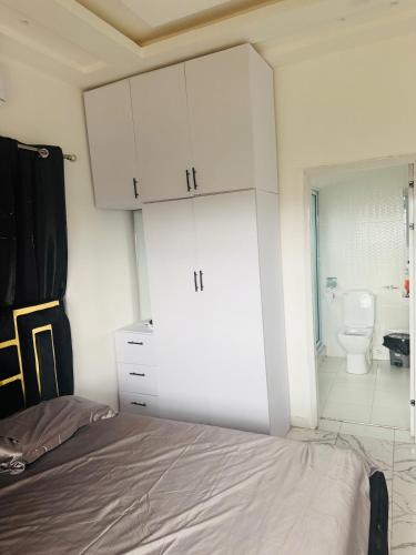 a bedroom with a bed and a bathroom with a toilet at Pebview 2 Bed Apartment in Kpone