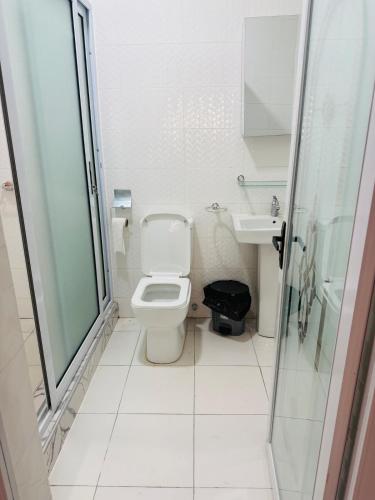 a white bathroom with a toilet and a sink at Pebview 2 Bed Apartment in Kpone