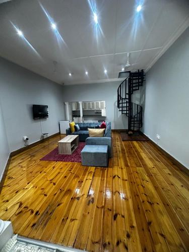 ein Wohnzimmer mit einem blauen Sofa und Holzboden in der Unterkunft Everly4 Guest Apartment in Durban