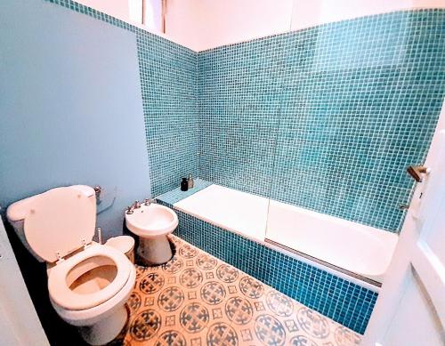 ein blau gefliestes Bad mit einem WC und einer Badewanne in der Unterkunft La Casa Rosada del Barrio Histórico in Colonia del Sacramento