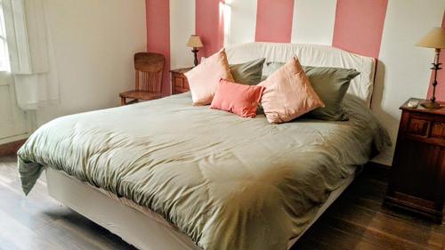 ein Bett mit rosa und grünen Kissen darauf in der Unterkunft La Casa Rosada del Barrio Histórico in Colonia del Sacramento