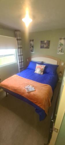 ein Schlafzimmer mit einem großen Bett mit blauer Bettwäsche in der Unterkunft Lyons Winkups Holiday Park Towyn, North Wales static Caravan 3 bedroom sleeps 8 free entertainment in Kinmel Bay