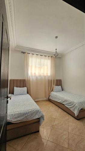 a bedroom with two beds and a window at Jad Appartement N1 in Essaouira