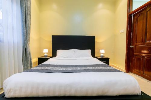 a bedroom with a large bed with two night stands at Equinox Vacation Apartments in Bulambiro