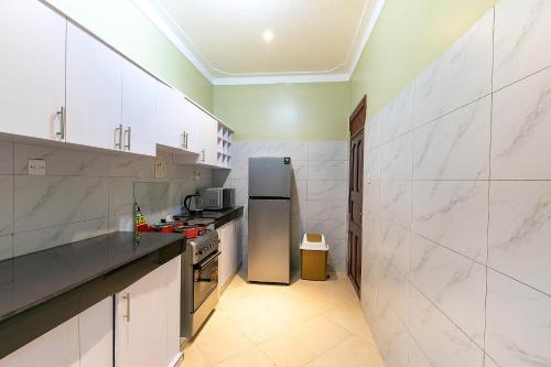 a kitchen with white marble walls and a refrigerator at Equinox Vacation Apartments in Bulambiro