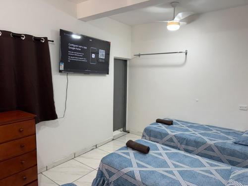 a room with two beds and a flat screen tv at Cozy house near Vila Aurora Station in Sao Paulo