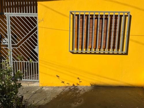 a yellow wall with a window with a metal grate at Cozy house near Vila Aurora Station in Sao Paulo