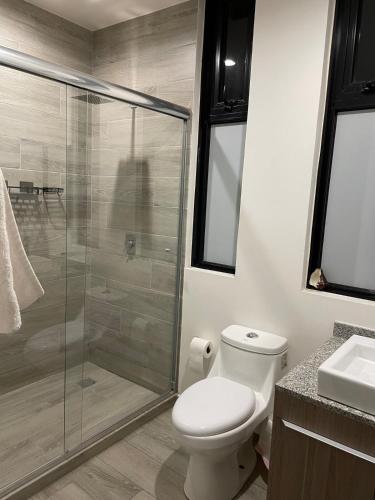 a bathroom with a toilet and a glass shower at Motto, Queretaro Departamento in Miranda
