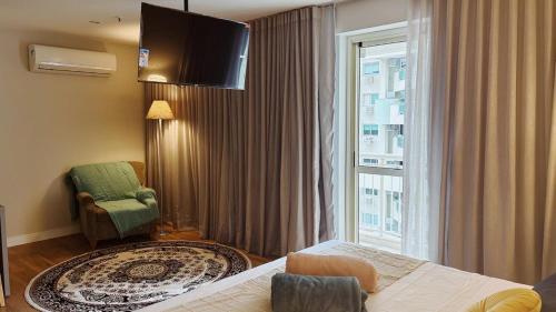 a hotel room with a bed and a chair and a window at Flat na Barra da Tijuca in Rio de Janeiro