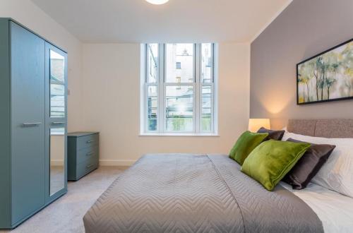 a bedroom with a large bed with green pillows at Hull Central Comfort in Hull