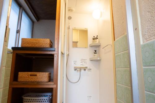 a bathroom with a shower with baskets on the wall at 中通りハウス in Zentsuji