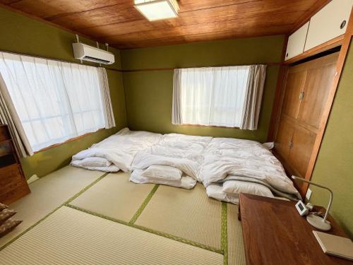 a large bed in a room with two windows at 中通りハウス in Zentsuji