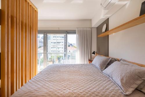 een slaapkamer met een bed en een groot raam bij Apartamento top 40m2 Trend 24 Moinhos de Vento in Porto Alegre