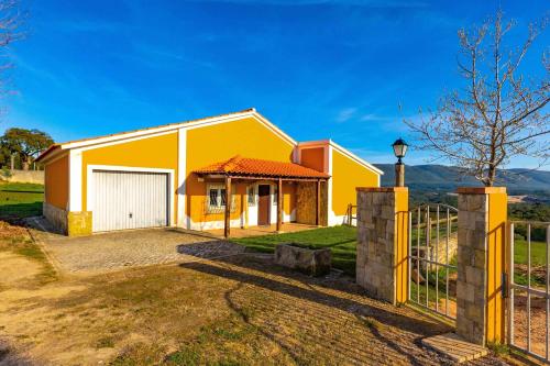 a yellow house with a gate and a fence at Casa De Campo Natureza in Porto de Mós