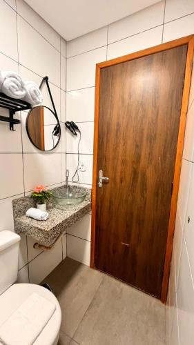 a bathroom with a wooden door and a sink at Studio em Ponta Porã in Ponta Porã