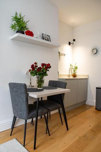 a dining room table with two chairs and a vase of flowers at City Nights, TV Bed, Free Parking, Nr Plymouth Hoe in Plymouth