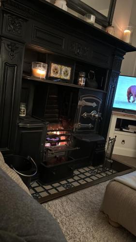 a fireplace in a living room with a tv at Lilac Cottage in Farington