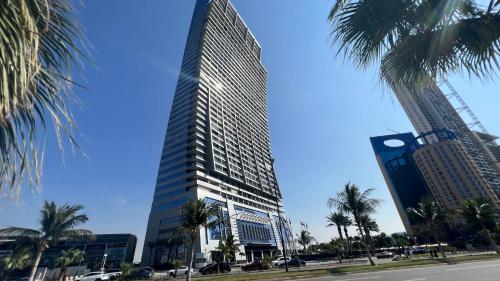 a tall building with palm trees in front of a street at شقة ثلاث غرف مطلة على البحر في برج داماك جدة in Jeddah